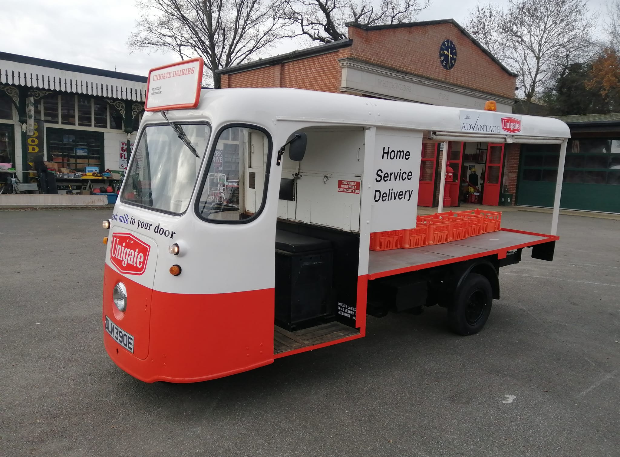 A red and white Unigate Dairies milk float with 'Home Service Delivery' on the side.